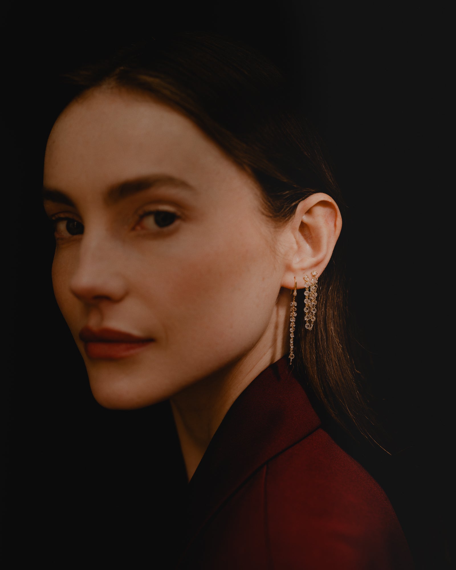 Close-up of a woman wearing elegant rose cut diamond and gold earrings against a dark background