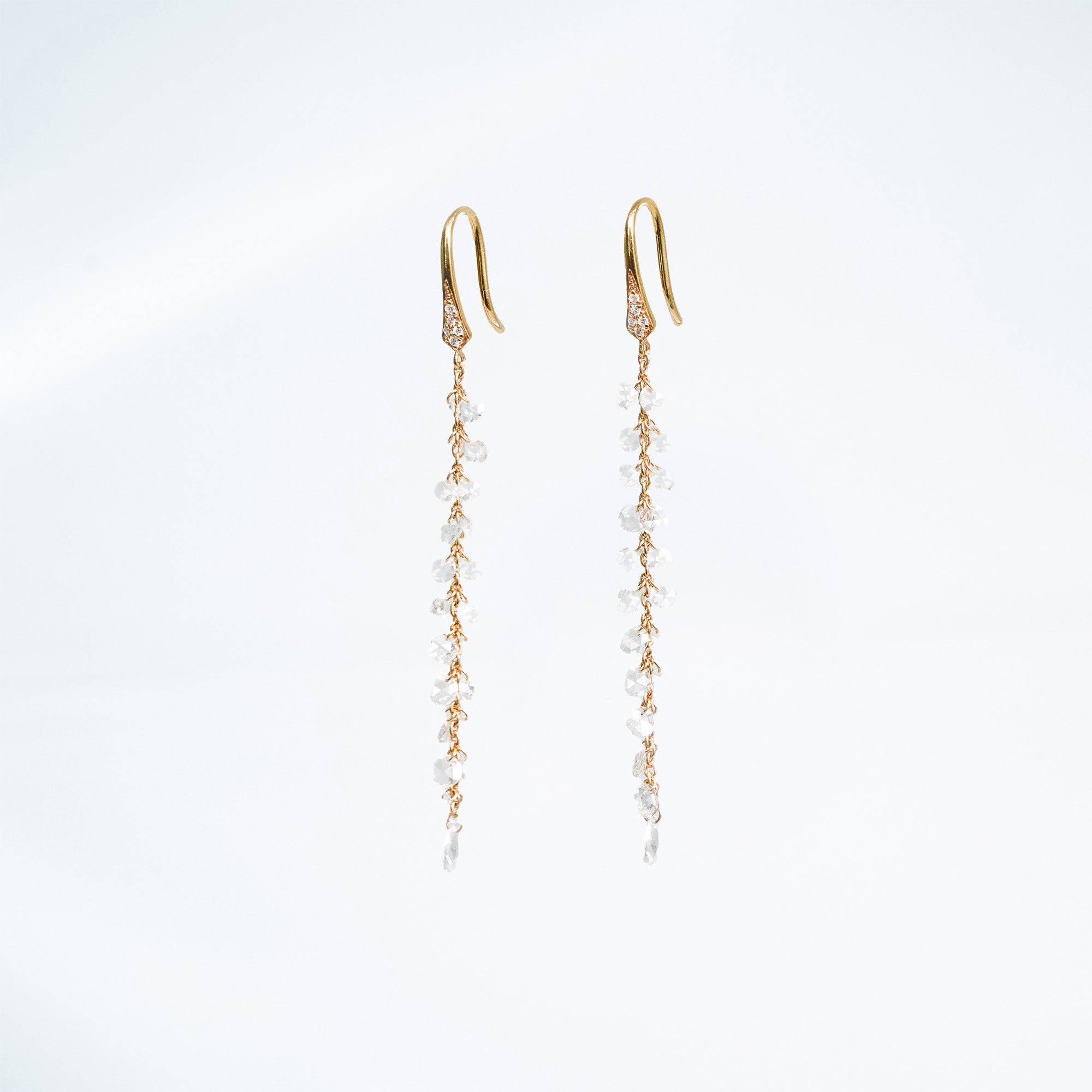 Gold earrings with rose cut diamonds on a light gray background