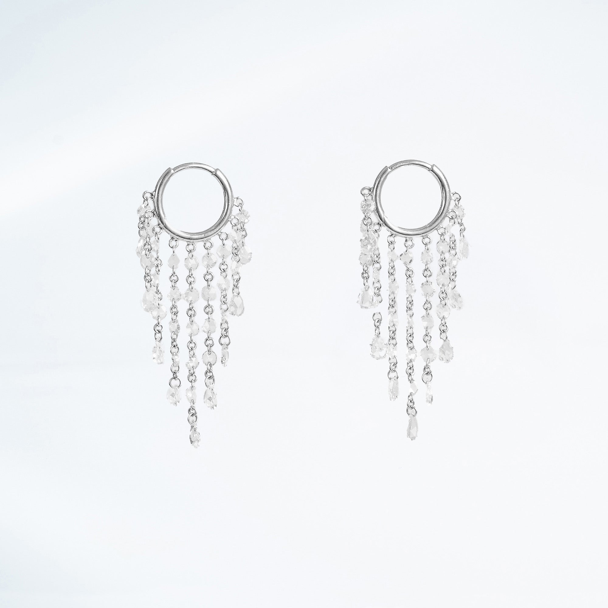 White gold hoop earrings with dangling chains of rose cut natural mined diamonds on a white background