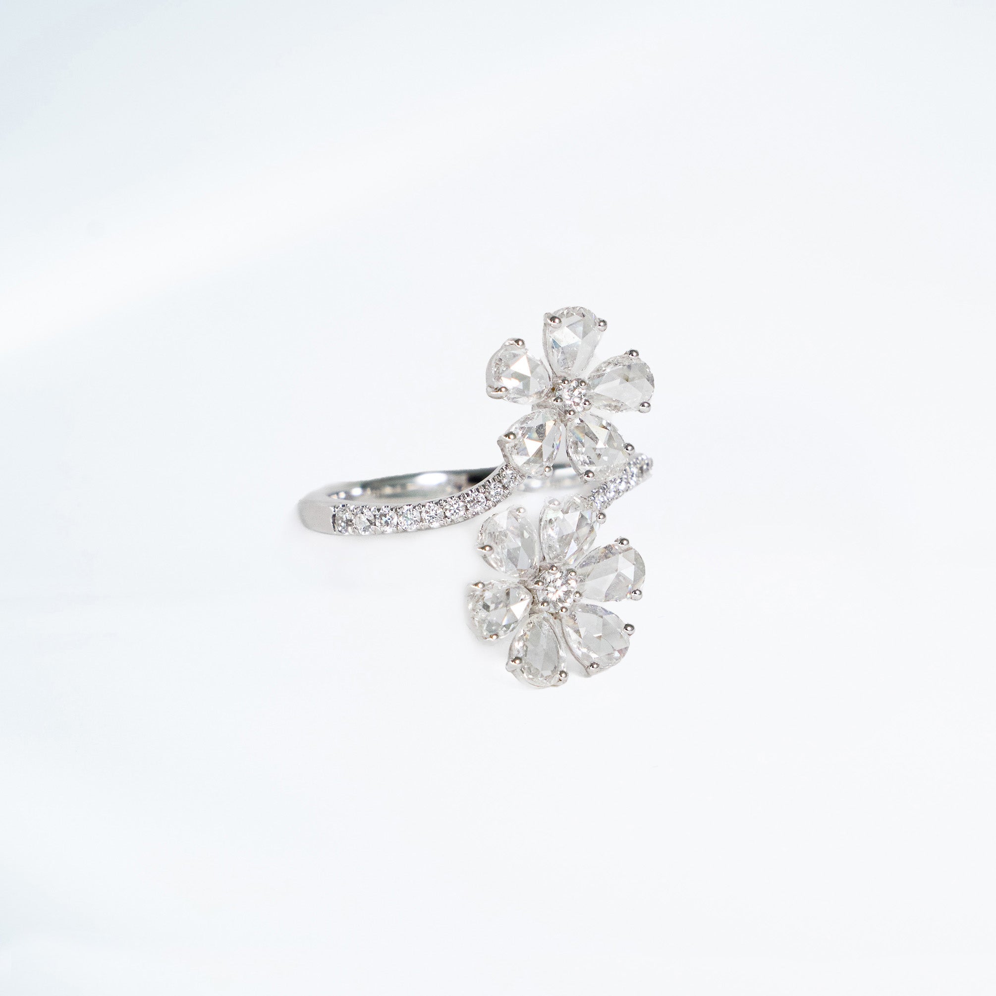Two flowers made out of rose cut natural mined diamonds set in 14k white gold with diamonds on the band around the flowers.