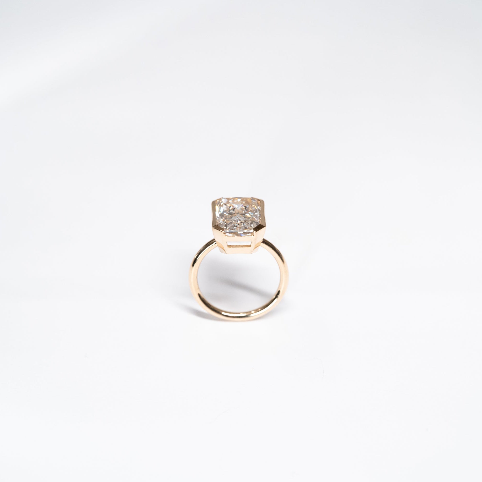 8 Carat lab diamond bezel set in 14k yellow gold side angle showing bottom of ring and bezel setting. 