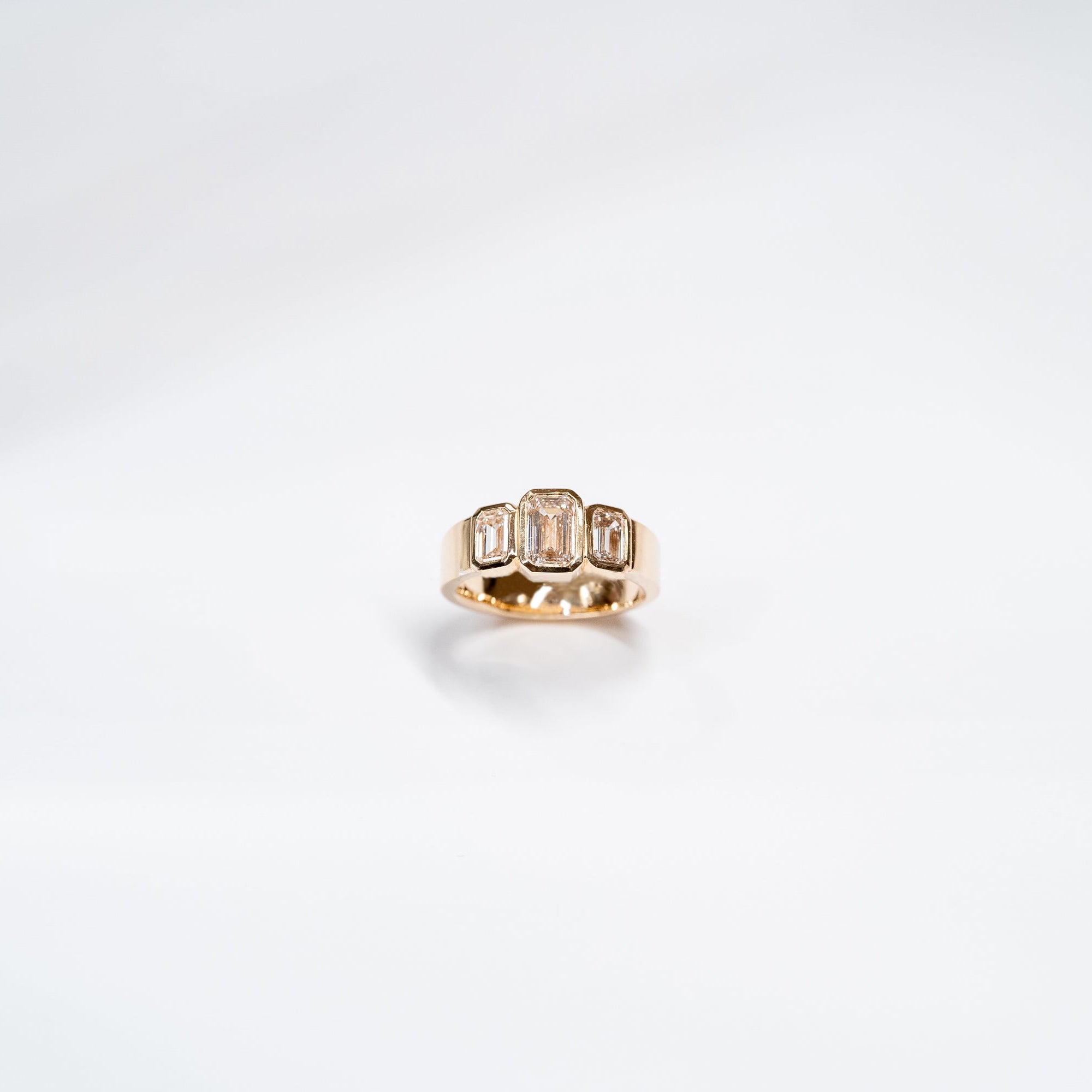 Three Lab Diamond Emerald Cut Ring set in 14k yellow gold.  Center Emerald Cut diamond is larger than two stones on the sides. 