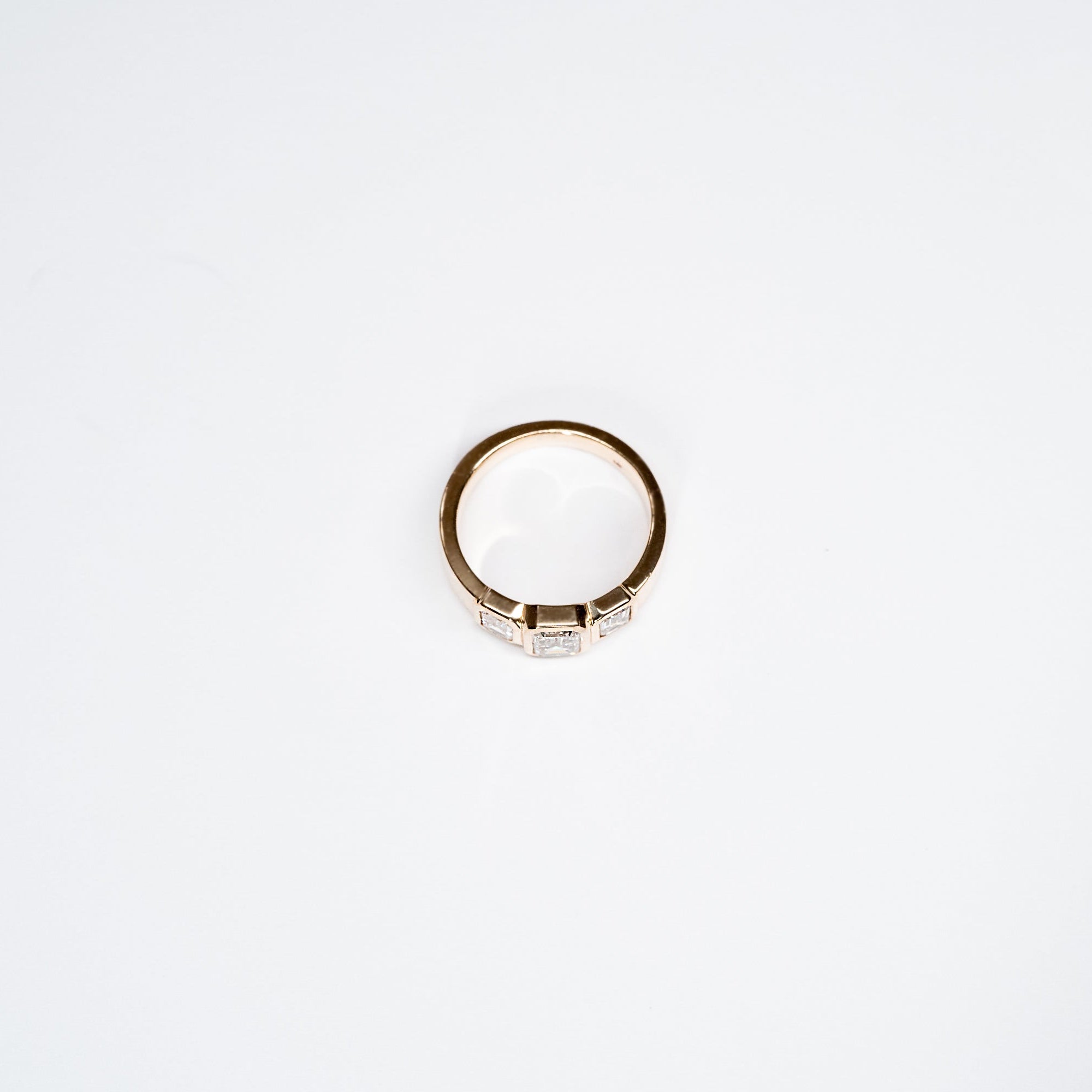 Side Profile of Three Lab Diamond Emerald Cut Ring set in 14k yellow gold.  Center Emerald Cut diamond is larger than two stones on the sides. 