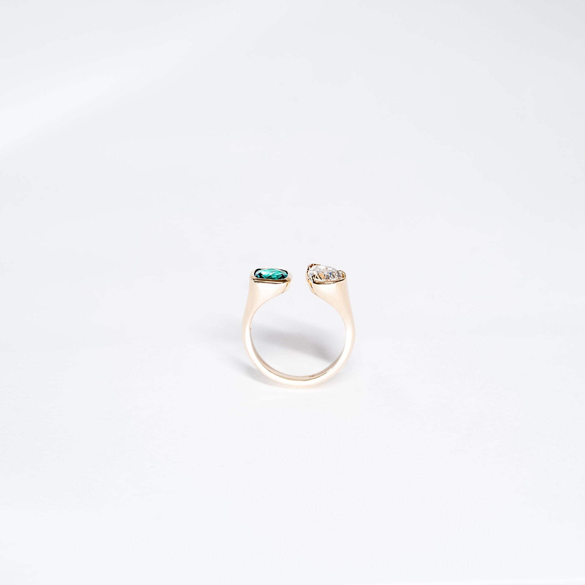 side angle Toi Et Moi Gold ring with emerald radiant stone and pear shaped diamond. 